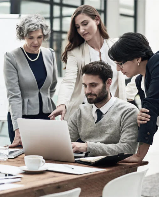 Four people discussing while looking at a laptop